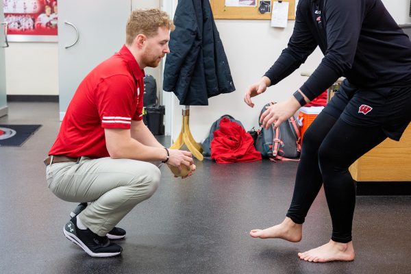 student assists an athlete with physical therapy